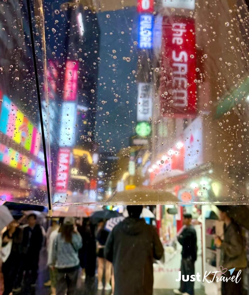 Tourist walking in rainy Myeongdong street during Korea rainy season