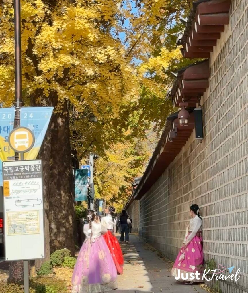 Visitors wearing hanbok at Gyeongbokgung Palace during autumn