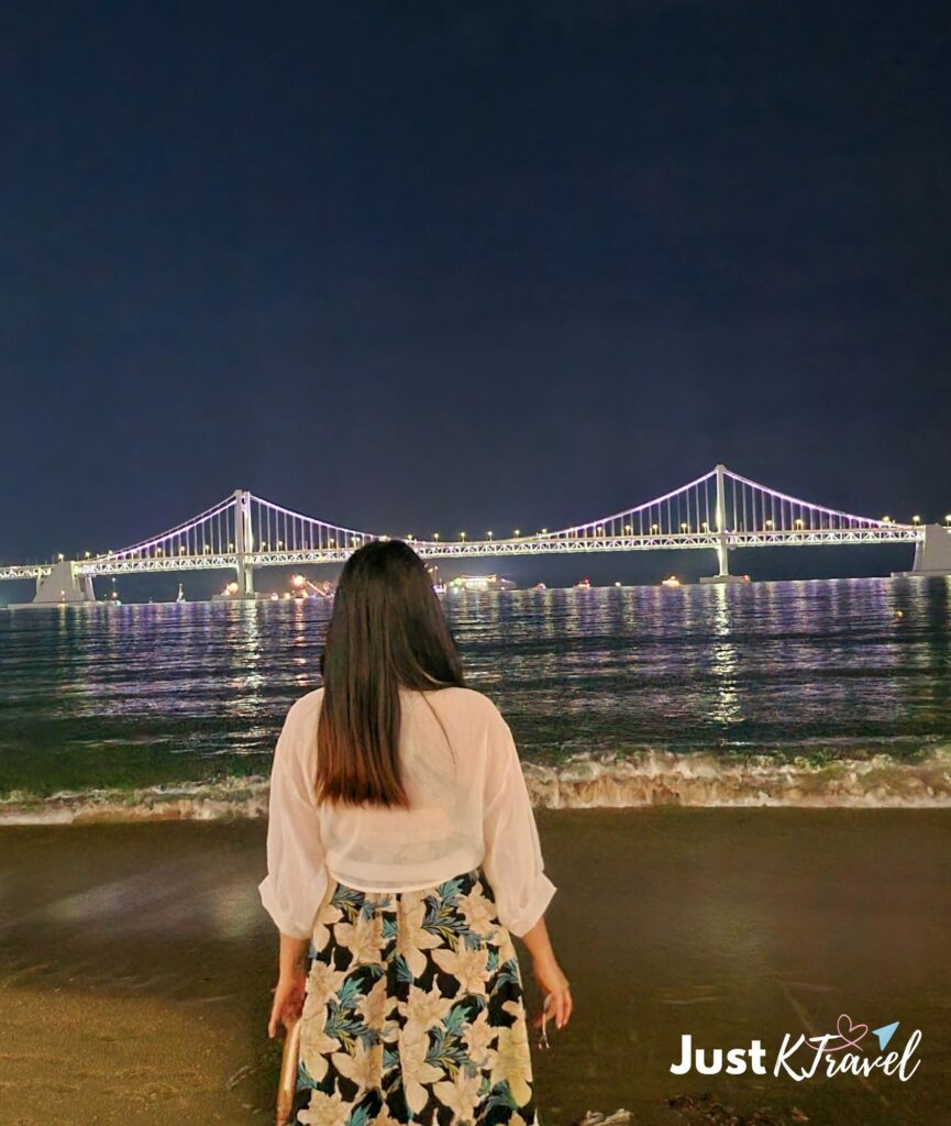Solo traveler enjoying the night view of Gwangalli Beach and Gwangan Bridge in Busan