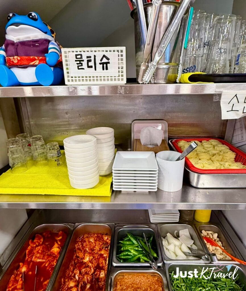Self-service banchan counter with Korean side dishes at a restaurant in Busan
