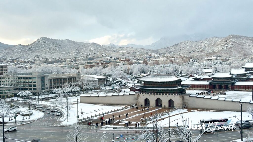 Gwanghwamun Gate covered in snow with a snowy mountain in the background